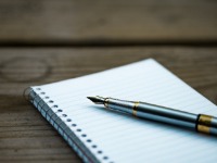 A blank page of a note book with a pen sitting on top