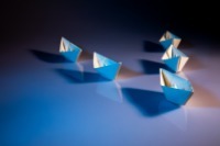 A collection of five paper boats arranged in formation