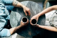 Two finance and accountancy colleagues sit opposite each other drinking coffee