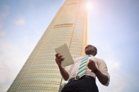 A smart businessman stands in front of a tall corporate building