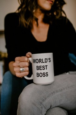 Woman with a cheerful expression, holding a mug that says "World's Best Boss," celebrating her role as a supportive leader.