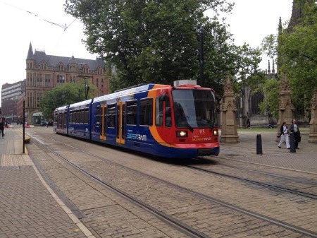A vibrant blue and orange Sheffield super tram positioned on the railway tracks.