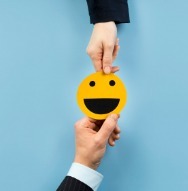 A group of business professionals holds a smiley face against a blue backdrop, representing employer loyalty and team spirit.