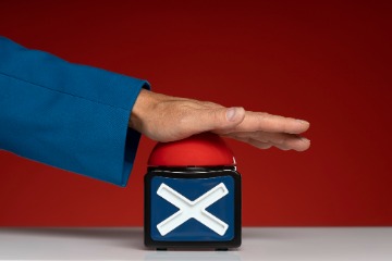 A hand grips a box featuring a red and blue cross, indicating a rejection or disapproval of something.