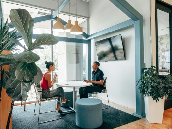 Two people seated at a table in an office, engaged in a job interview.