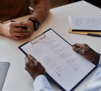 Two people discussing a CV while seated at a table, focused on the document in front of them.