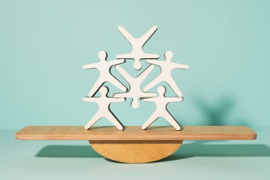 A wooden figurine depicting people balanced on a scale, symbolizsing fair treatment of part-time staff.