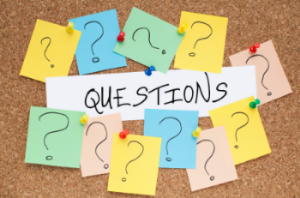 A cork board filled with colorful question cards, showcasing various inquiries and ideas pinned with pushpins.