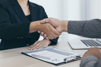 A handshake between two individuals over a desk, representing collaboration and mutual understanding.