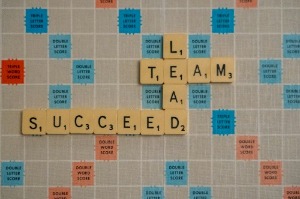 Scrabble board displaying the word "team success" formed with colorful letter tiles.