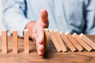 A man displays a wooden block before a domino, representing the concept of establishing work boundaries.