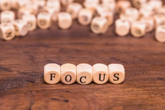 Wooden dice on a table spell "focus," illustrating the concept of resetting one's focus in a work environment.