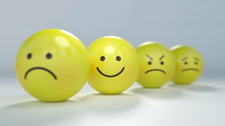Four yellow smiley faces, two happy and two sad, representing the theme of managing emotions effectively.