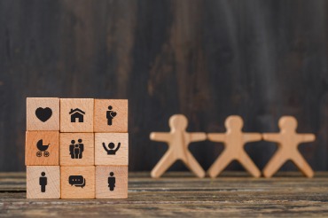 Wooden cubes with icons of individuals and families, representing the challenges posed by insufficient employment benefits.