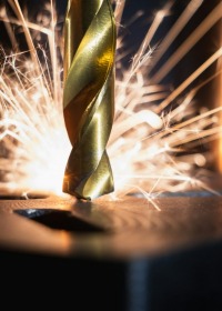 Detailed view of a metal milling machine, highlighting its gears and cutting tools in action.