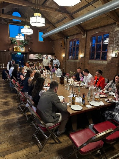  A group of accounting professionals networking at a long table during a late evening event for future CFOs.