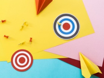 Vibrant paper targets and airplanes on a lively background, illustrating the alignment of goals between employees and businesses.