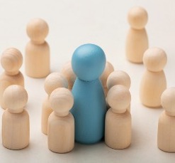 A wooden figure is surrounded by a diverse group of people, representing unity and inclusive leadership in action.
