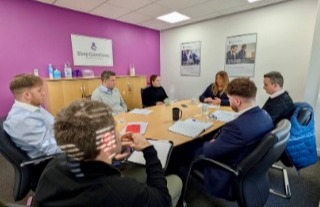  A diverse group of people engaged in a meeting about workplace equality for International Women's Day.