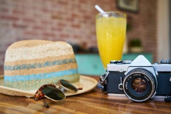 A table displays a camera, hat, sunglasses, and a drink, representing an accountant's vacation vibe.