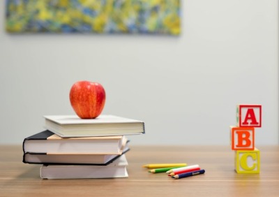 An apple, colorful pencils, and ABC blocks arranged on a table in a private school setting.