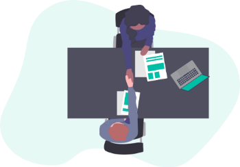 Two colleagues discussing staff appraisals at a table, surrounded by papers and laptops.