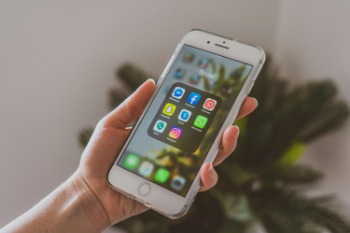 A person holding an iPhone displaying apps aimed at boosting accountants' online presence.