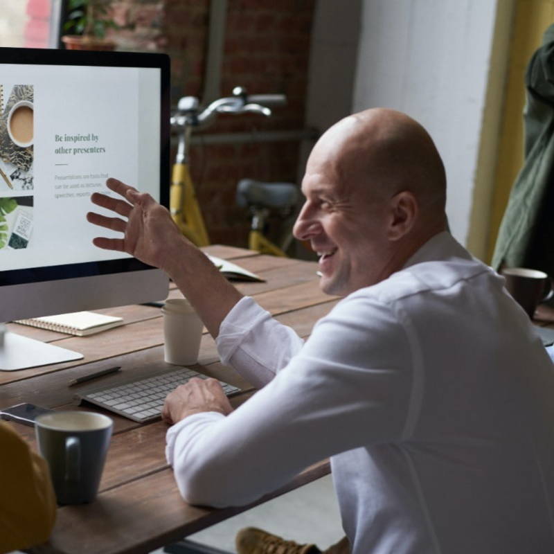 A man in a white shirt looks at accountancy and finance information on a PC screen
