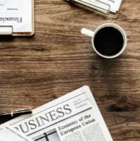 A business office desk featuring a laptop, scattered papers, and various office supplies arranged neatly.
