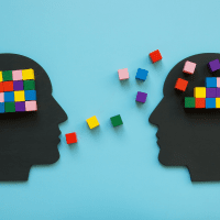 Two heads adorned with vibrant paper cutouts, symbolising creativity and mentoring in a collaborative environment.