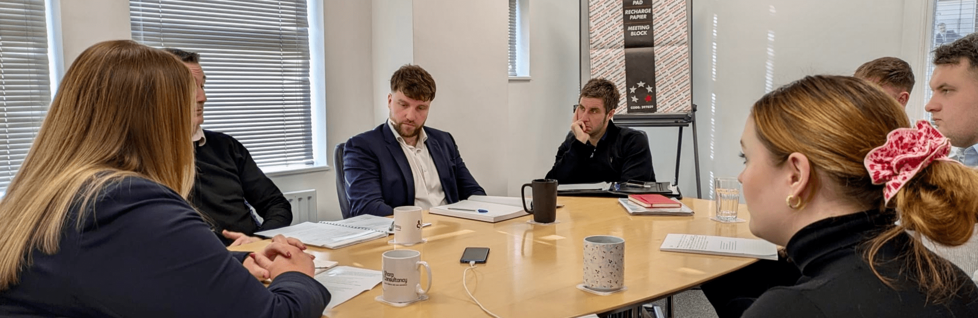 A meeting room scene with individuals discussing equality in the workplace for International Women's Day.
