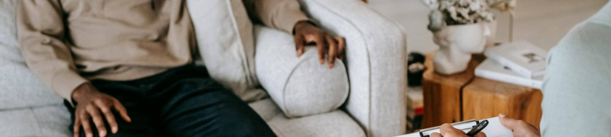 A recruitment consultant advises a finance candidate on a couch, both focused on the clipboard in her hands.