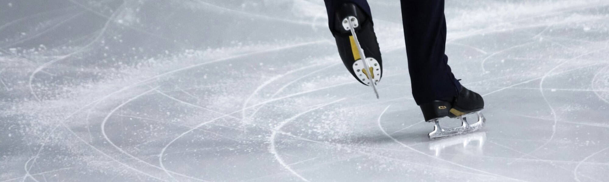 A man figure skating in a competition on an ice rink.