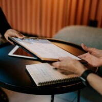 A woman holds a clipboard with her Transactional Finance CV on it while a man reviews the CV.